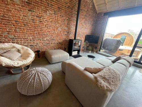 a living room with two couches and a brick wall at Boven de paarden @ de Hoeveschuur in Riemst