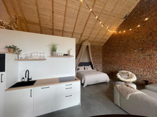 a kitchen and living room with a brick wall at Boven de paarden @ de Hoeveschuur in Riemst