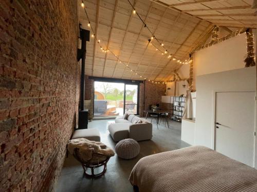a living room with a brick wall and a couch at Boven de paarden @ de Hoeveschuur in Riemst