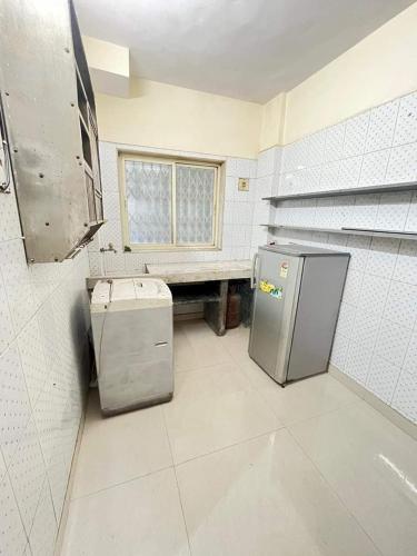 F1 apartments في مومباي: مطبخ فيه ثلاجة ومقعد