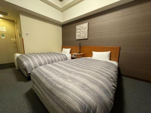 Hotel Route-Inn Asahikawa Ekimae Ichijodori في اساهيكاو: غرفه فندقيه سريرين في غرفه