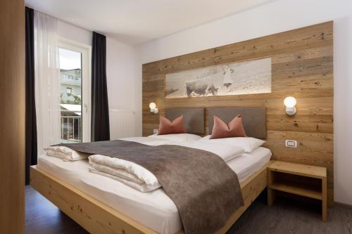 Dolomite Apartments Winklwiese 6&7 في سان كانديدو: غرفة نوم بسرير كبير وبجدار خشبي
