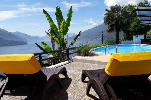einen Pool mit gelben Stühlen und Blick auf das Wasser in der Unterkunft Ferienwohnung für 5 Personen ca 69 m in San Carlo, Comer See Westufer Comer See in Gravedona