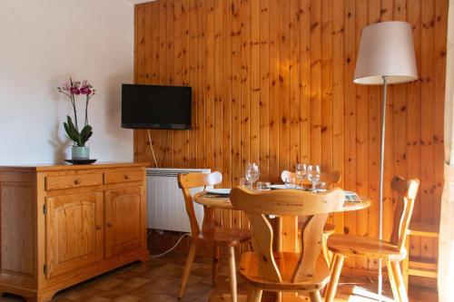 une salle à manger avec une table, des chaises et une télévision dans l'établissement Briançon studio à seulement 200m des pistes !, à Briançon