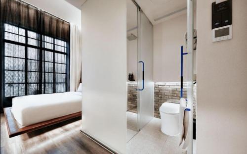 a bedroom with a bed and a glass door with a toilet at Z Hotel Shanghai Bund Shamei Building in Shanghai