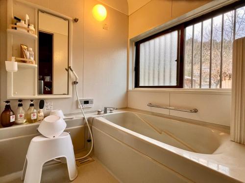 uma casa de banho com uma banheira, um lavatório e uma janela em beau lac biwako em Takashima