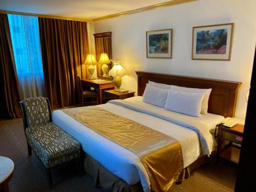 a hotel room with a bed and a chair at Maharaja Oriental Suite Makati in Manila