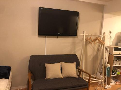sala de estar con silla y TV de pantalla plana en Station Front SHINIMAMIYA 501, en Osaka
