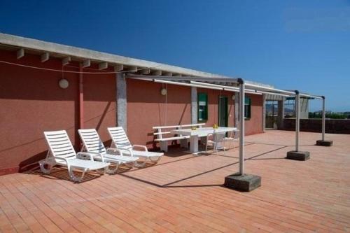 - un ensemble de chaises blanches et d'une table sur une terrasse dans l'établissement Ferienwohnung für 6 Personen ca 50 qm in Giardini Naxos, Sizilien Ostküste von Sizilien, à Giardini Naxos