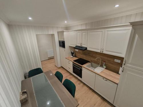 Una cocina con gabinetes blancos y una mesa y sillas. en ApartmanyHurbanova1, en Bardejov