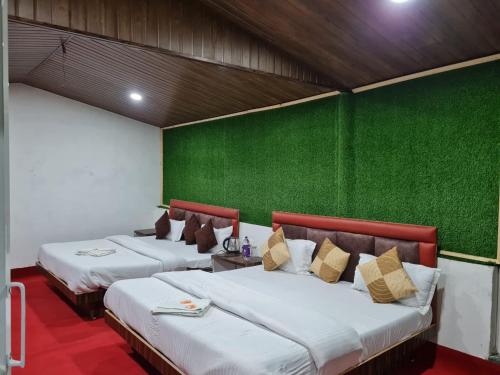 two beds in a room with a green wall at Cascade Resort And Cottages in Mussoorie