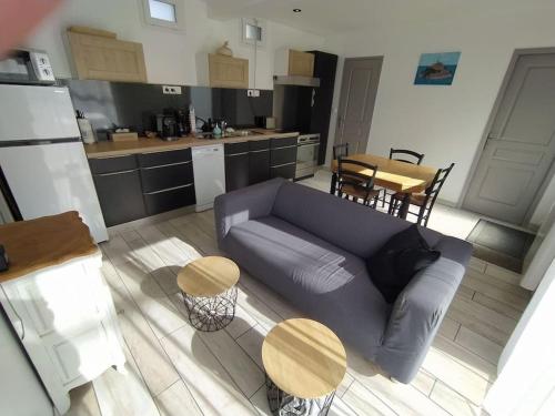 un salon avec un canapé bleu et une table dans l'établissement La Chaloupe gites de mer, à Jullouville