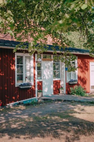a red house with a white door and windows at Hasselö Hostel in Hasselö