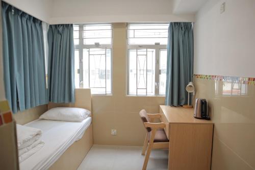 a small room with a bed and a desk and window at Comfort Hostel in Hong Kong