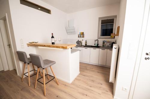 a white kitchen with a counter and two stools at Landhaus Oase im Herzen Oberviechtachs in Oberviechtach