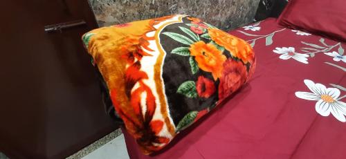 a blanket on a bed with flowers on it at Aggarwal guest house lajpat nagar, rooms with private kitchen Android tv wifi and fridge in New Delhi