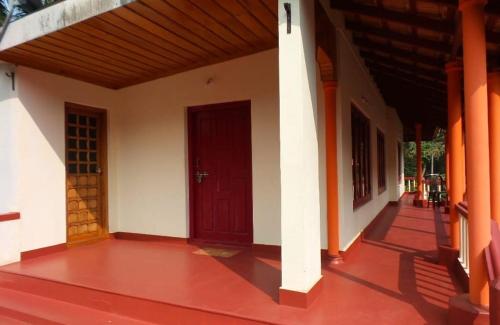 an empty porch of a house with a red door at Coorg Divine spark home stay in Suntikoppa