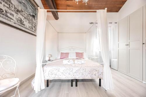 een witte slaapkamer met een hemelbed met roze kussens bij Residenza Bra Verona in Verona