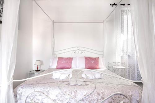 a white bedroom with a large bed with pink pillows at Residenza Bra Verona in Verona