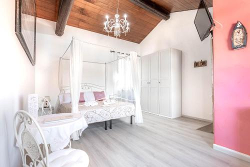 a white bedroom with a bed and a chandelier at Residenza Bra Verona in Verona