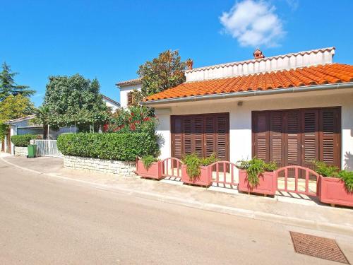 uma casa branca com persianas vermelhas numa rua em Ferienwohnung für 4 Personen ca 38 qm in Pjescana Uvala, Istrien Istrische Riviera em Pjescana Uvala