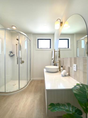 a bathroom with a shower and a sink and a mirror at The Views - Omokoroa in Omokoroa