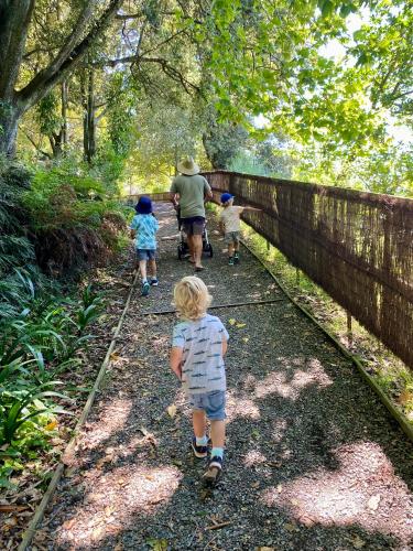 a man and three children walking down a trail at The Views - Omokoroa in Omokoroa