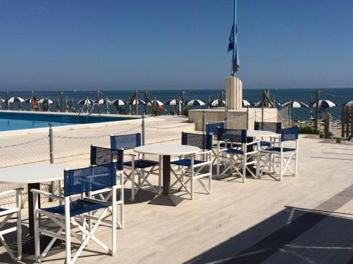 a patio with tables and chairs next to the ocean at Hotel Marcelli in Numana