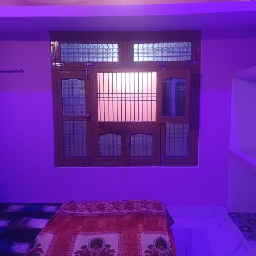 Habitación púrpura con cama y ventana en Maa Durga niwas home stey en Ayodhya