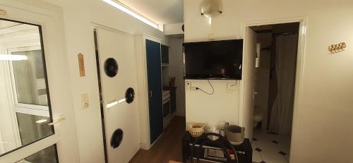 un salon avec une télévision et une chambre avec un réfrigérateur dans l'établissement T2 à 2 pas du centre-ville, à La Grande Motte