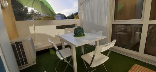 d'une petite table et de chaises blanches sur un balcon avec un parasol dans l'établissement T2 à 2 pas du centre-ville, à La Grande Motte