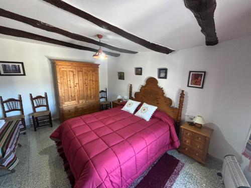 a bedroom with a large bed with a pink bedspread at Casa Pepo in Pampaneira