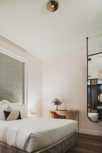 a white bedroom with a large bed and a mirror at Hôtel Singulier Bordeaux - Boutique Hôtel & Spa Anne Semonin in Bordeaux