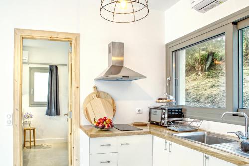 eine Küche mit weißen Schränken und einem Waschbecken in der Unterkunft Kumquart estate- Orange in Aspiotádes