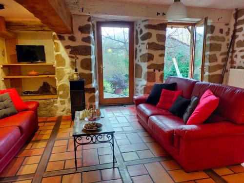 a living room with two red couches and a table at gîte Lo Jaç de Foart 10 pers. in Bosas