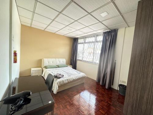 a bedroom with a bed and a desk and a window at Seladah Stay in Kuching