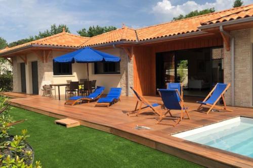 une terrasse en bois avec des chaises et une piscine dans l'établissement Belle maison avec piscine chauffée Lège Cap Ferret, à Lège-Cap-Ferret
