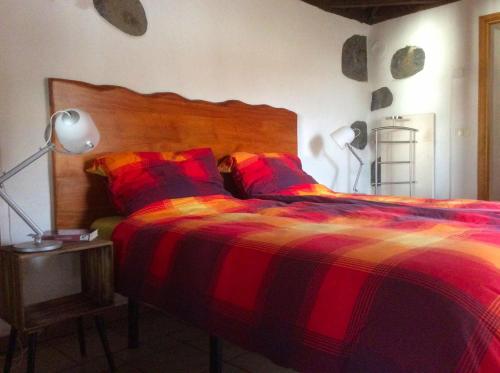 a bedroom with a bed with a red and orange blanket at Casa Visioneros Tijarafe LaPalma in Casaquemada