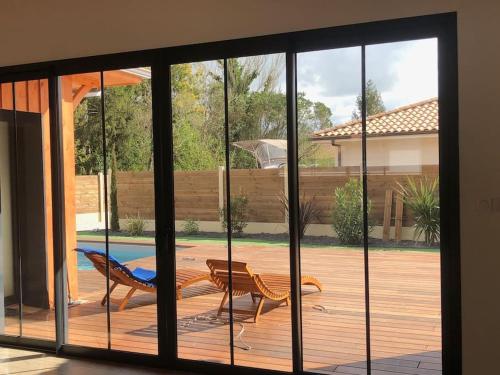 - une vue sur le patio par une porte coulissante en verre dans l'établissement Belle maison avec piscine chauffée Lège Cap Ferret, à Lège-Cap-Ferret