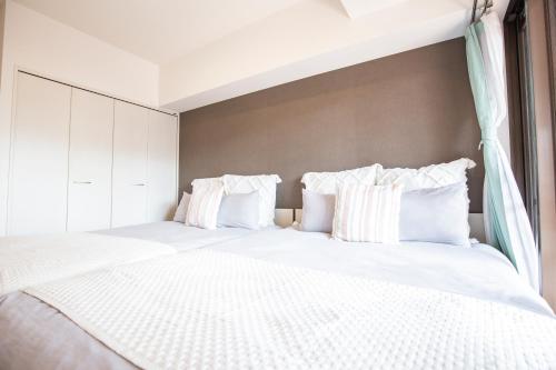 um quarto com uma cama grande com lençóis brancos e almofadas em Walk to Ikebukuro Station. SioS3 em Tóquio