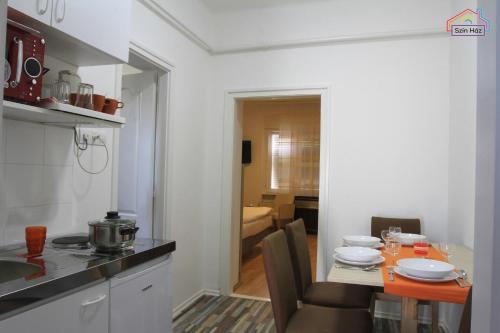 a kitchen with a table and a dining room at Szín-Ház Apartman in Gyula