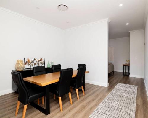 a dining room with a wooden table and black chairs at Modern Home in the Heart of Bankstown in Bankstown