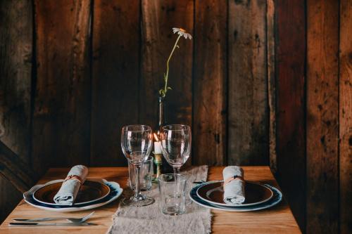 a table with glasses and plates and a vase with a flower at Hasselö Hostel in Hasselö