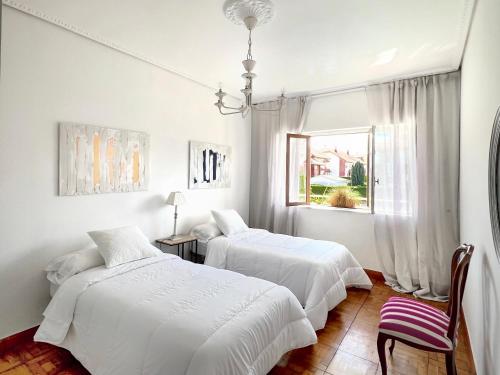 two beds in a white room with a window at Camino del Soplao -zona Santillana del Mar- in Reocín