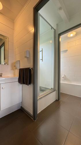 a bathroom with a shower and a large mirror at Central Court Motel in Whangarei