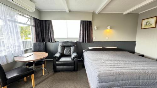 ein Schlafzimmer mit einem Bett, einem Stuhl und einem Tisch in der Unterkunft Central Court Motel in Whangarei