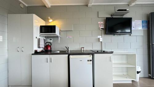 a kitchen with a sink and a tv on the wall at Central Court Motel in Whangarei