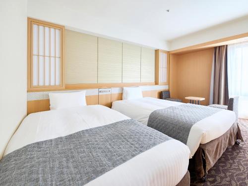 two beds in a hotel room with windows at Vessel Hotel Campana Kyoto Gojo in Kyoto