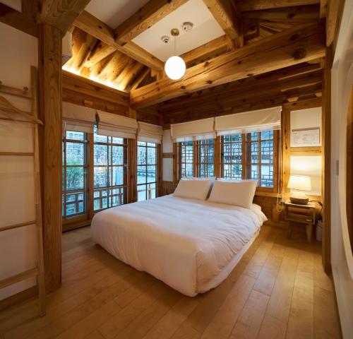 a bedroom with a white bed and wooden ceilings at Luxury hanok with private bathtub - SN01 in Seoul