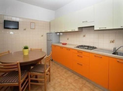 eine Küche mit orangefarbenen Schränken und einem Tisch darin in der Unterkunft Studio für 5 Personen ca 48 qm in Bibione, Adriaküste Italien Bibione und Umgebung - b59957 in Bibione